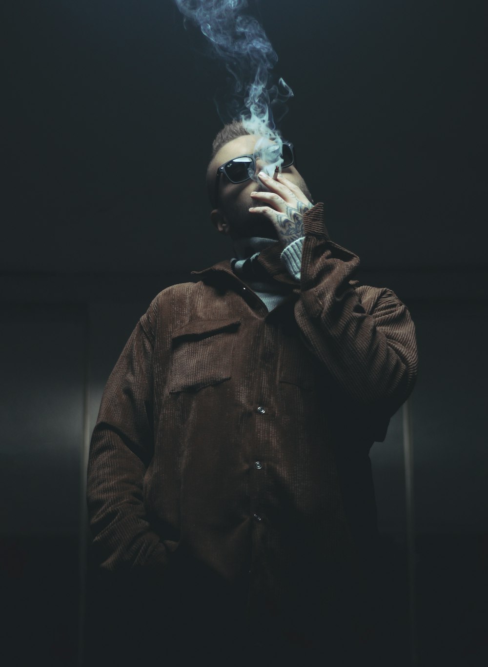 hombre en chaqueta de cuero marrón fumando cigarrillo