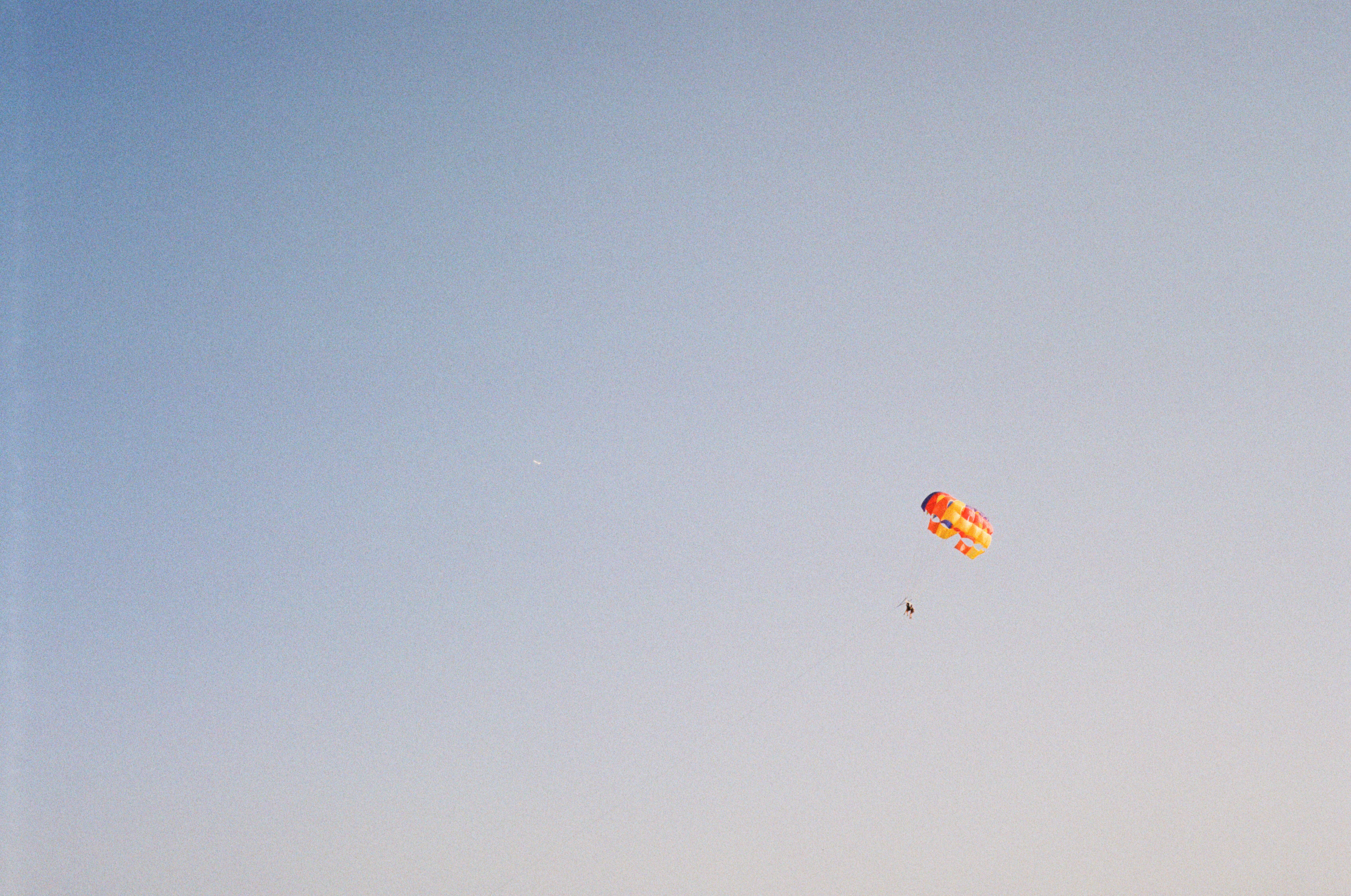 red and yellow parachute under blue sky during daytime