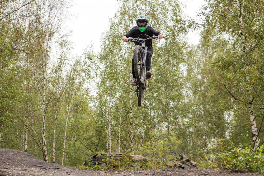 man in black jacket riding bicycle on forest during daytime