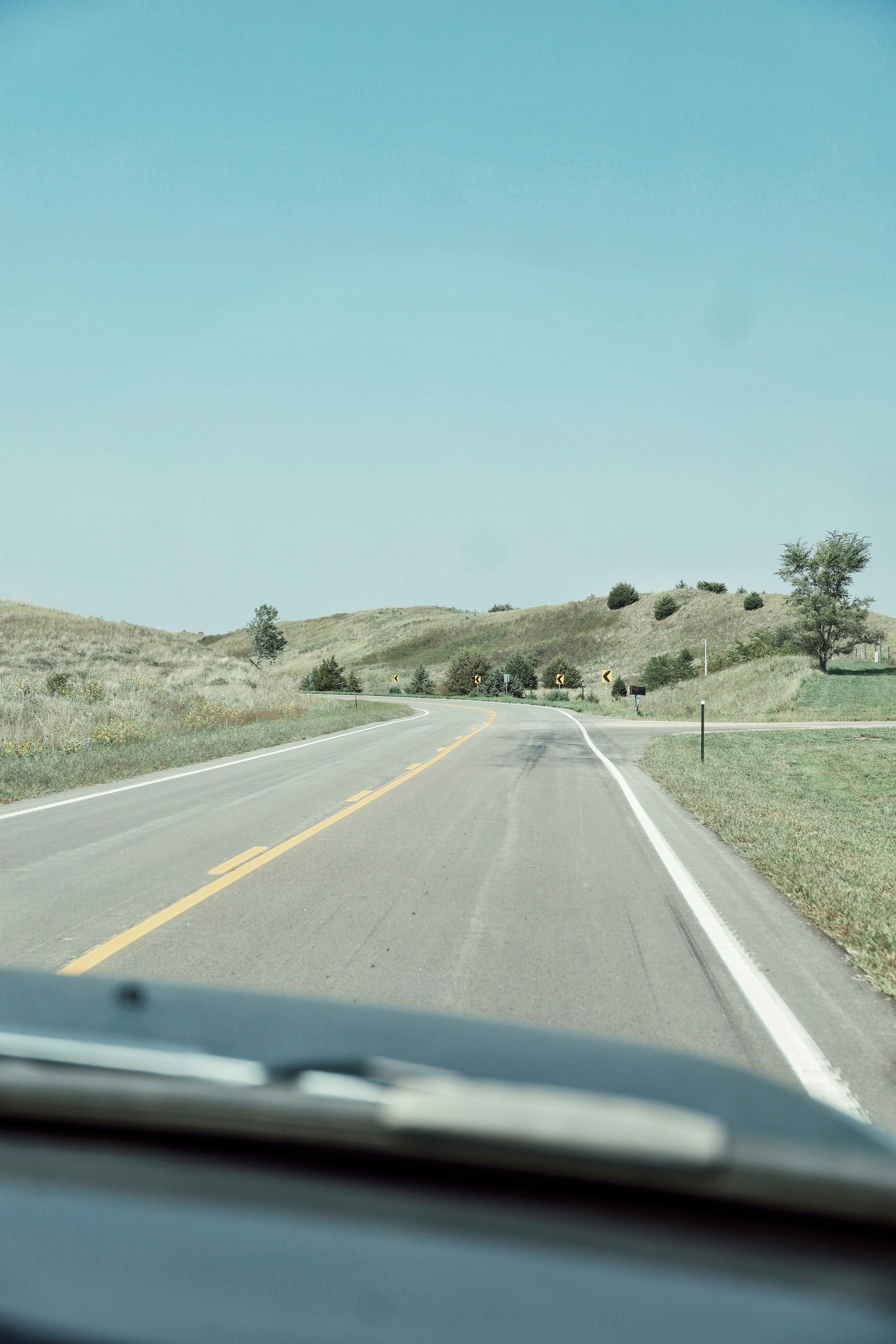 gray concrete road between green grass field under blue sky during daytime