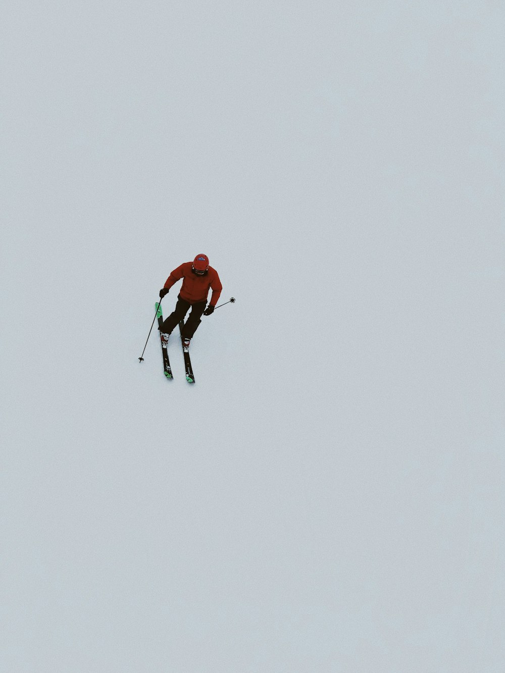 man in red jacket and black pants walking on snow covered ground during daytime