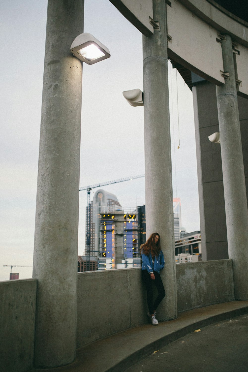 woman in black jacket standing near gray concrete post during daytime