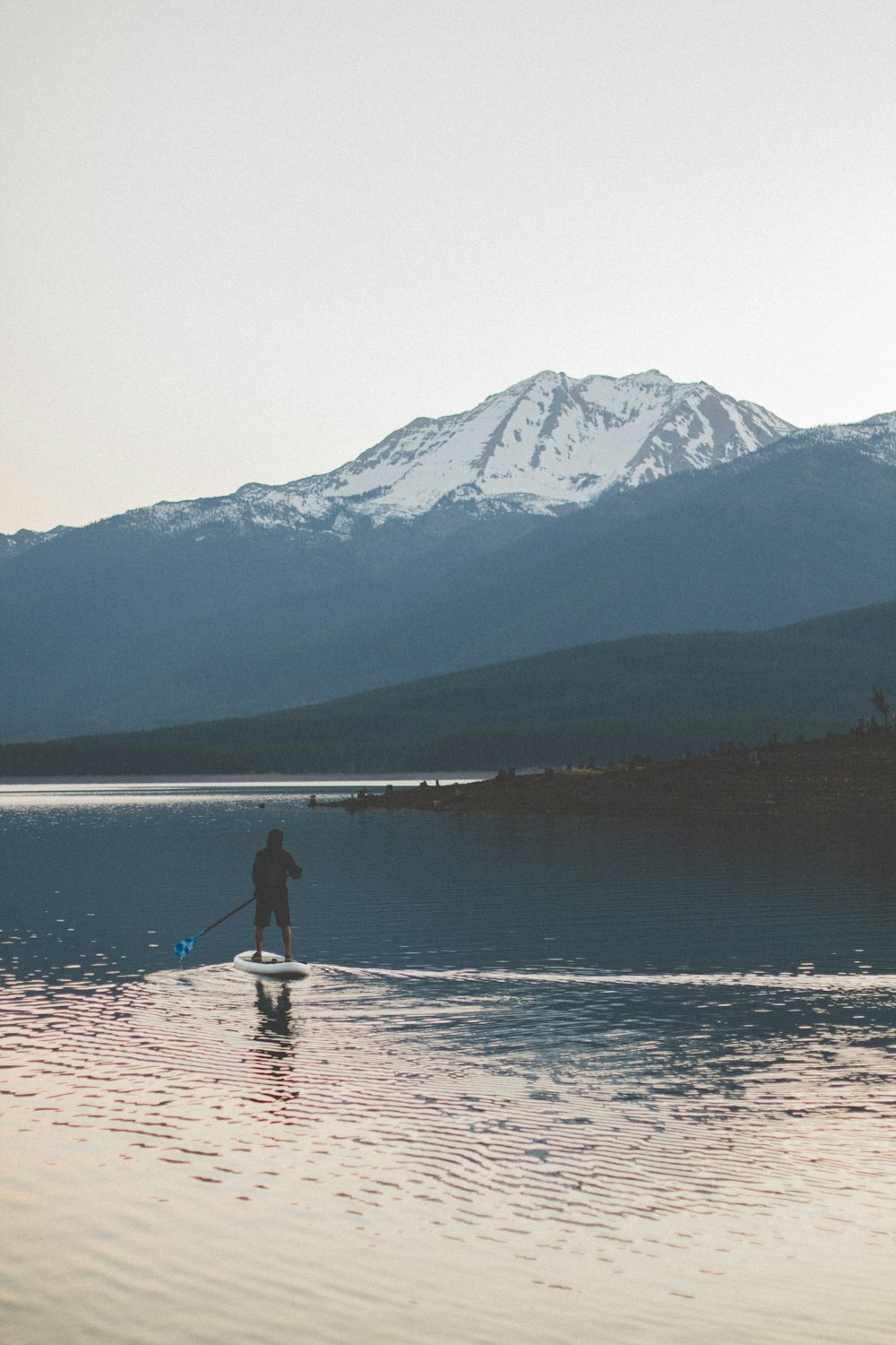 man in black jacket and blue denim jeans standing on boat on lake during daytime