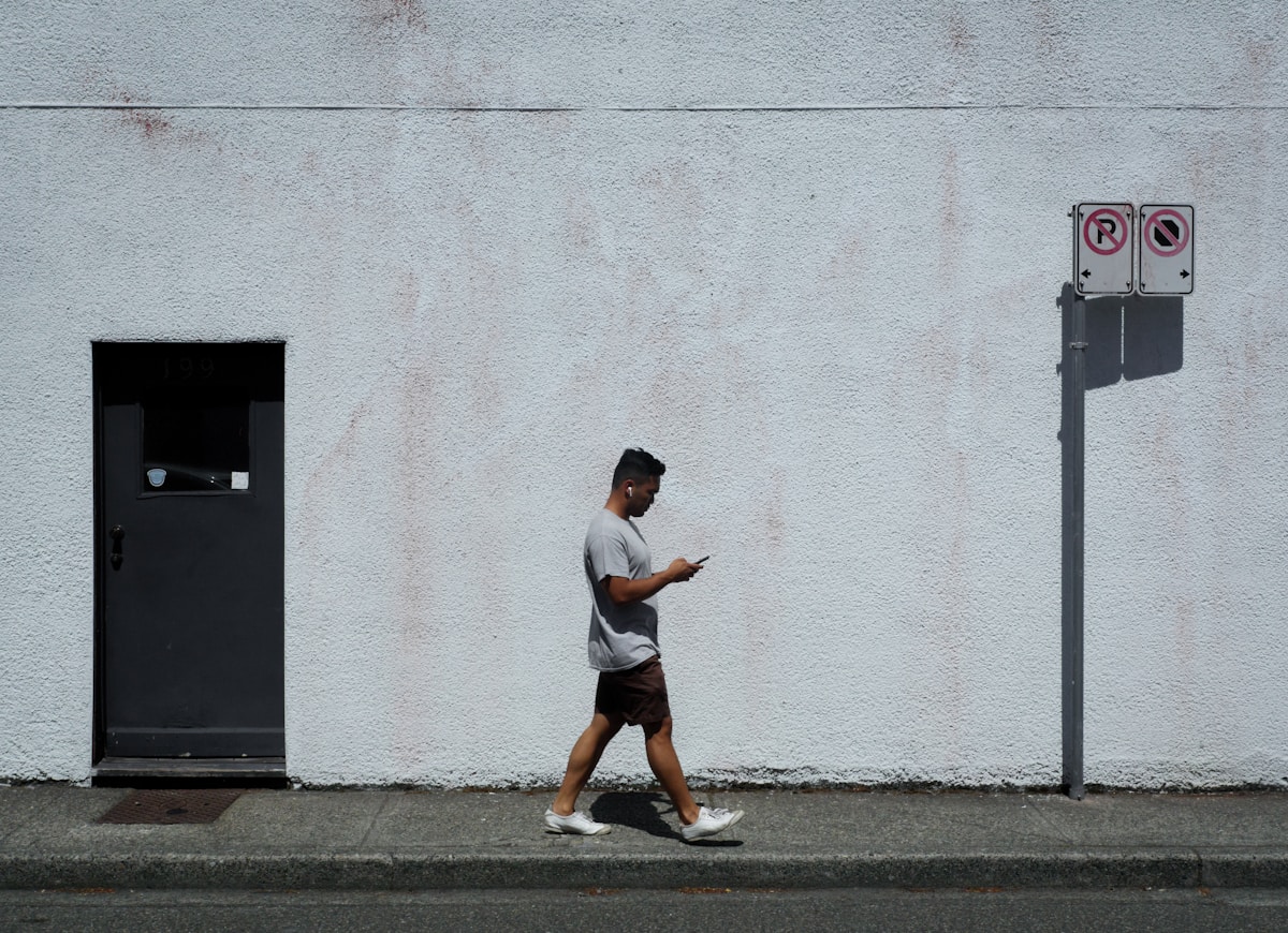 man in white t-shirt and brown shorts running on gray concrete pavement
