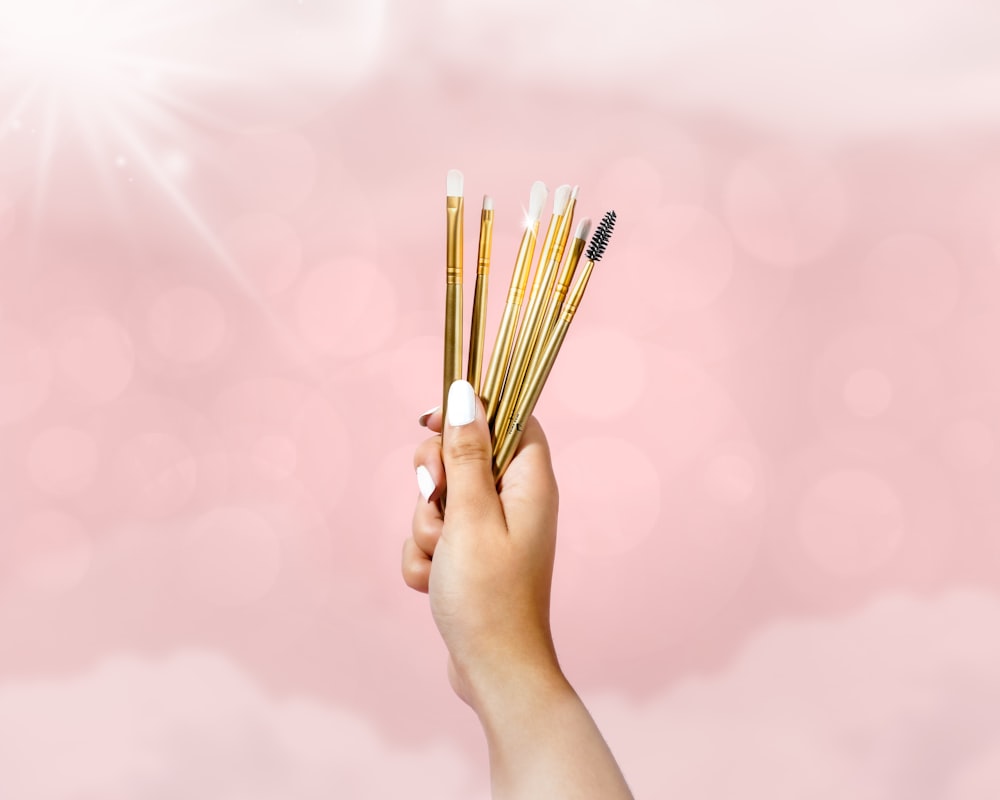 person holding brown sticks on pink background