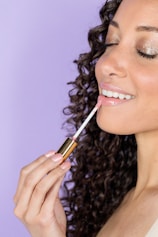 woman holding black and gold lipstick