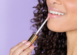 woman holding black and gold lipstick