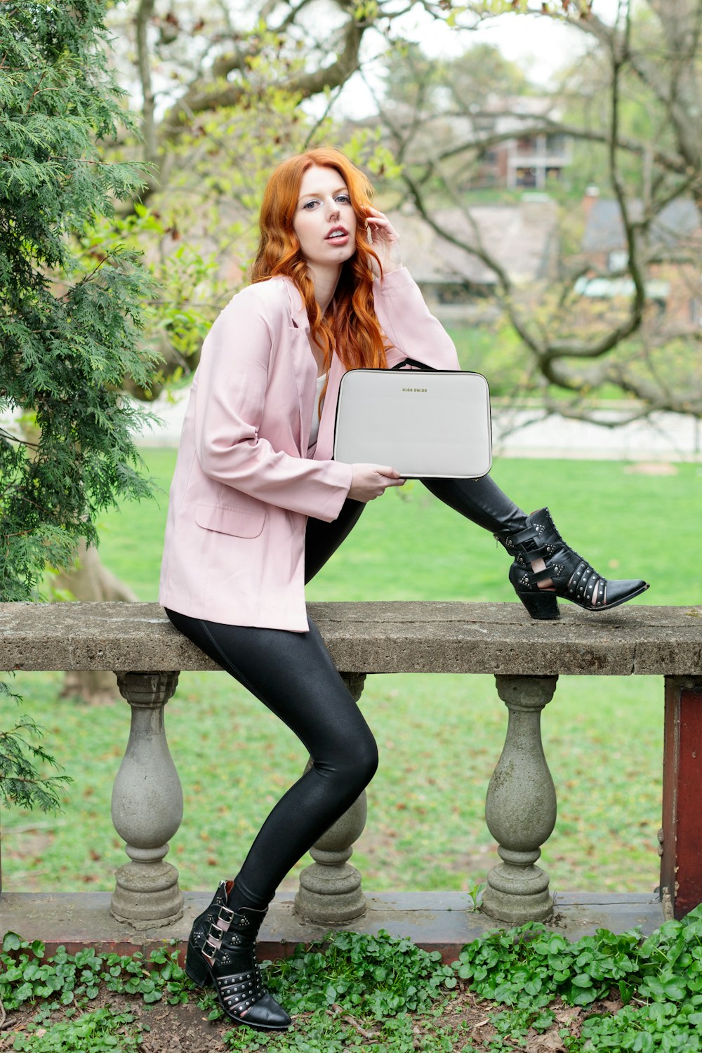 woman in pink blazer and black pants sitting on brown wooden bench