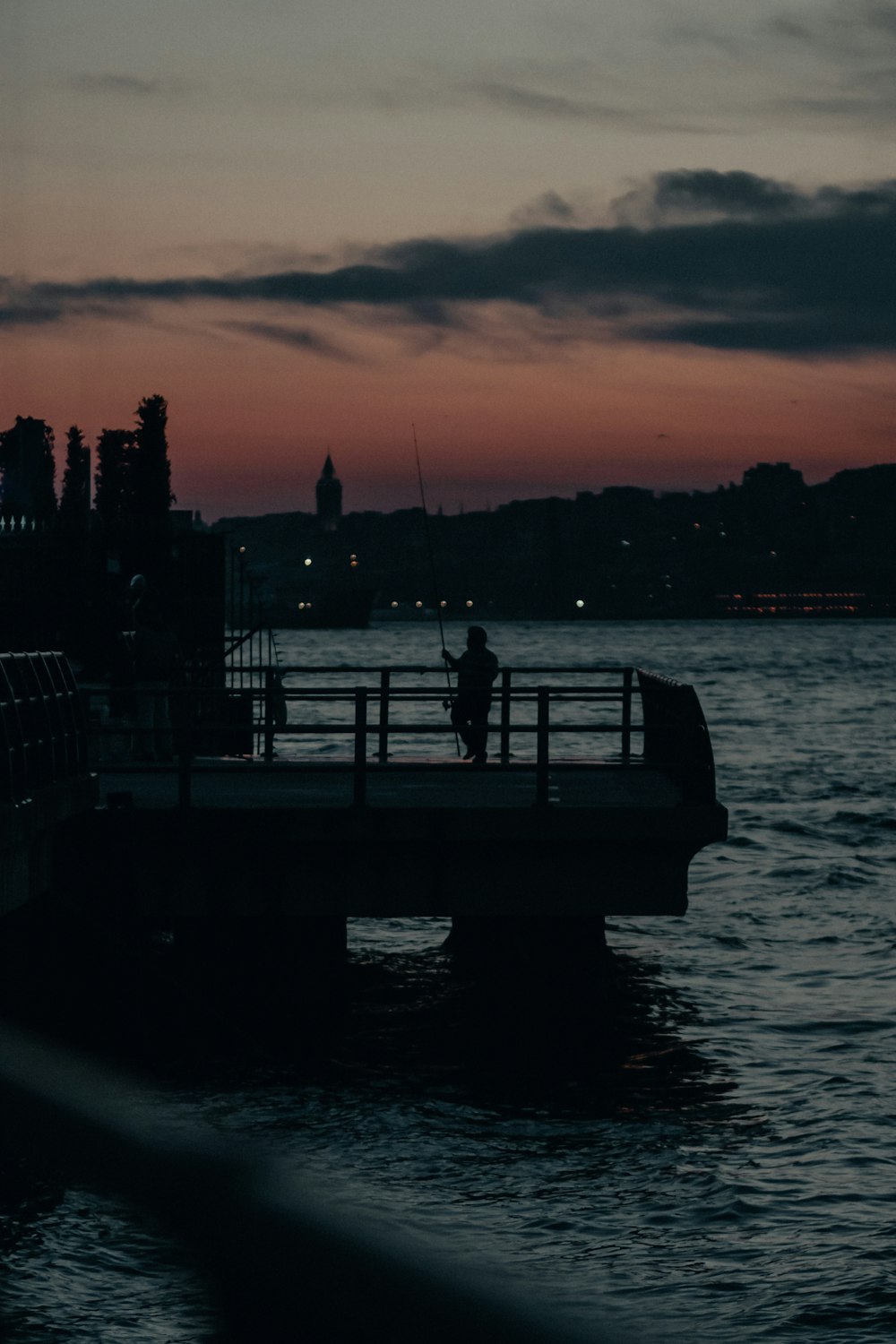 man and woman sitting on dock during sunset