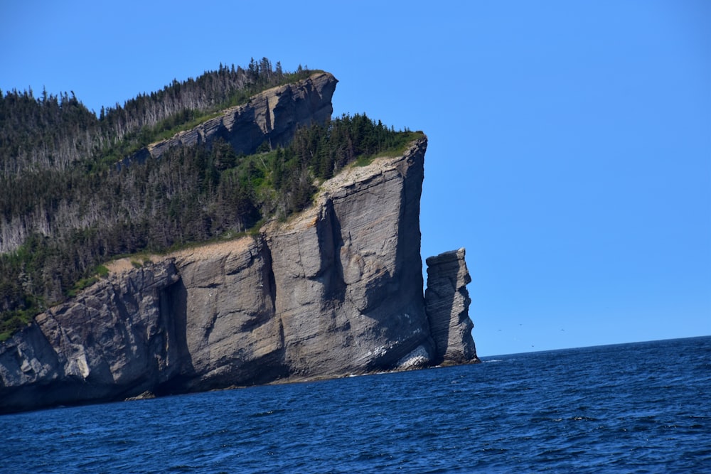 gray rock formation beside blue sea under blue sky during daytime