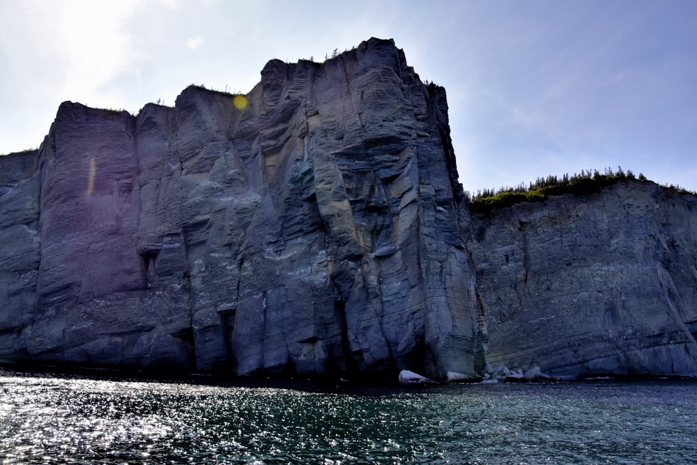 gray rocky mountain beside body of water during daytime