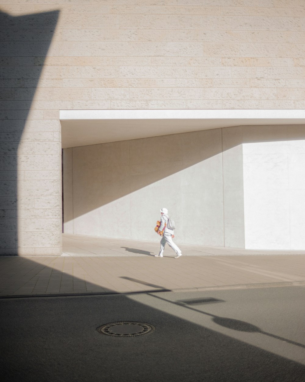 man in white shirt and pants walking on sidewalk during daytime