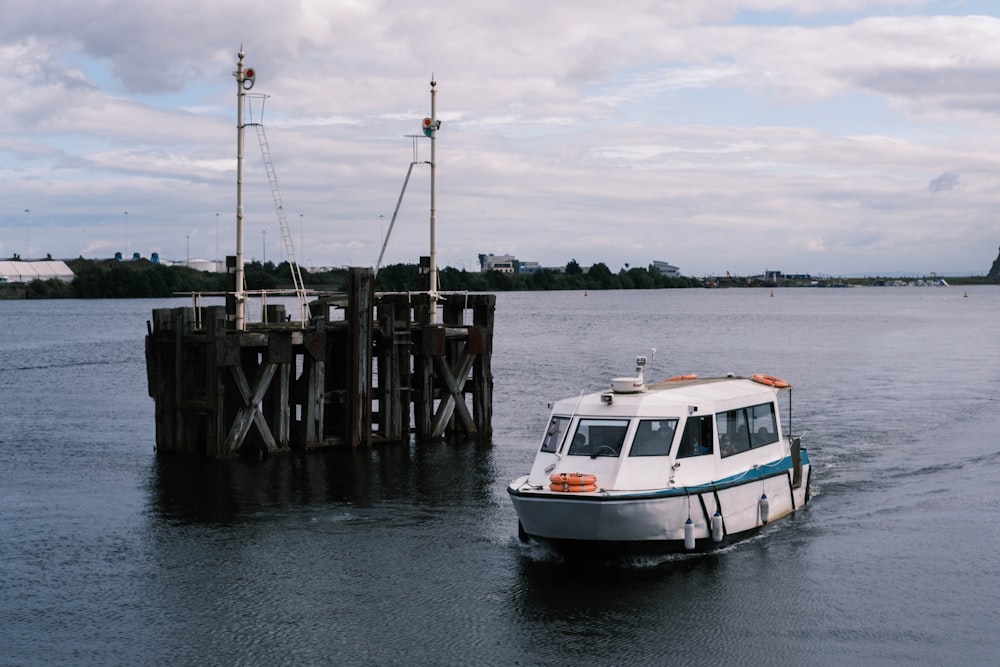 Weißes und blaues Boot auf See Dock unter bewölktem Himmel während des Tages