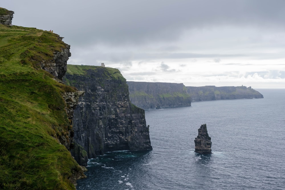 green and gray rock formation on body of water during daytime