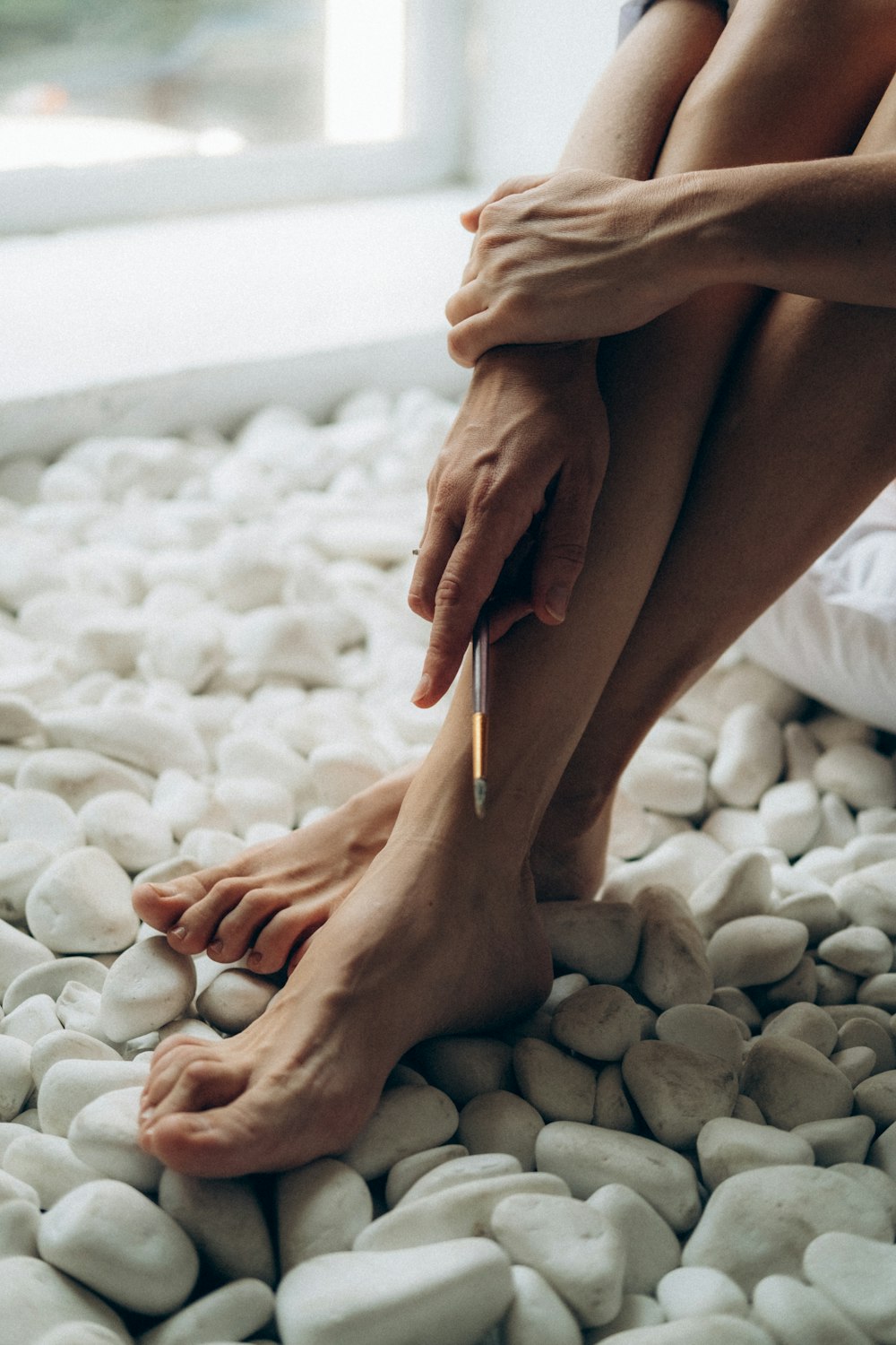 persons feet on white and gray pebbles