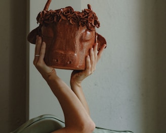 person holding brown ceramic pot