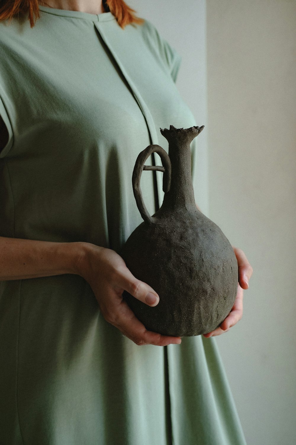 person holding brown and black ceramic vase