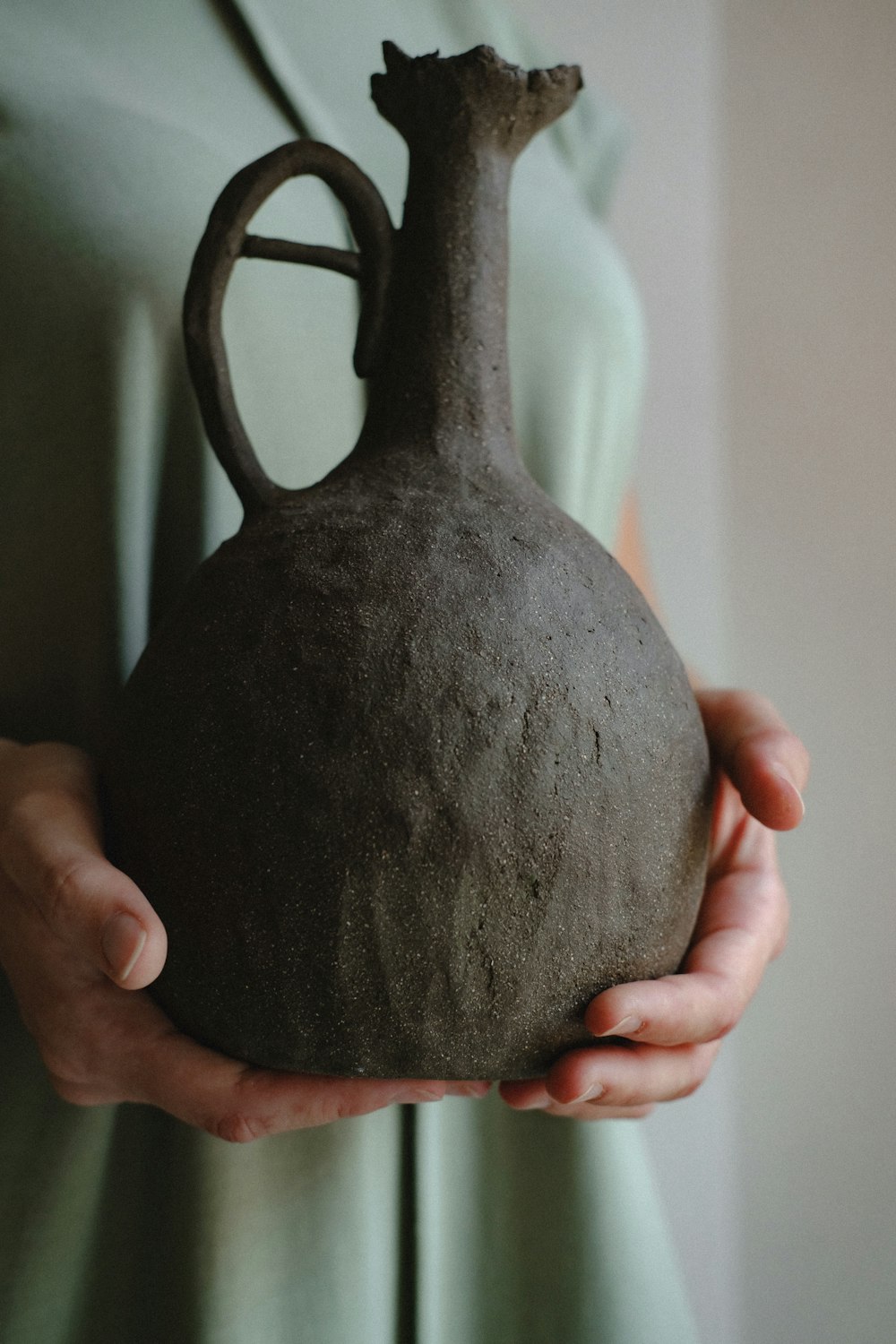 person holding brown ceramic vase