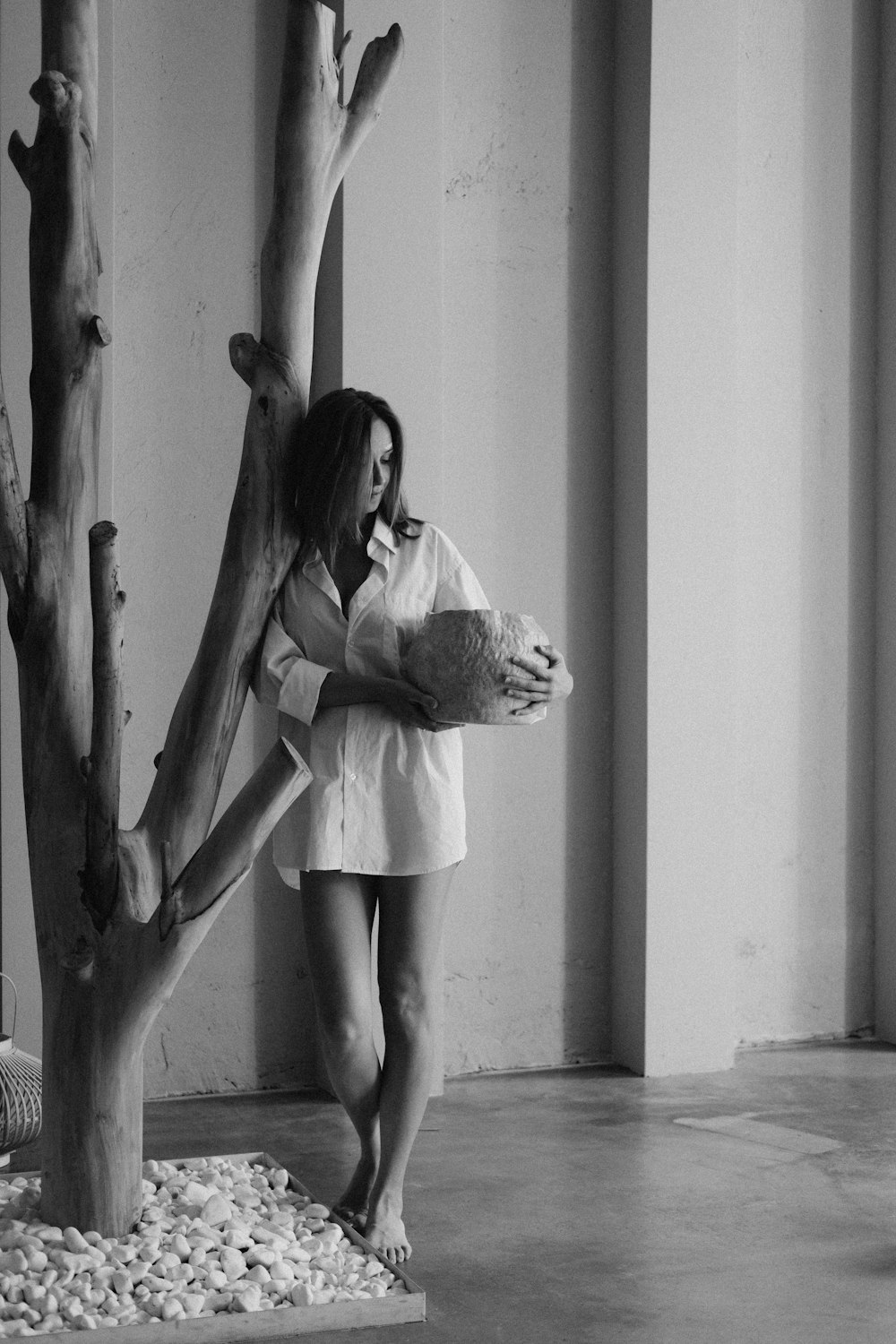 grayscale photo of woman in white dress leaning on wall