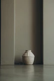 A bright, hand-thrown vase with playful patterns, placed among soft linens and dried flowers.