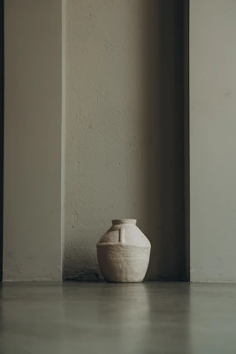 A rustic handmade ceramic vase with earthy tones on a wooden table.