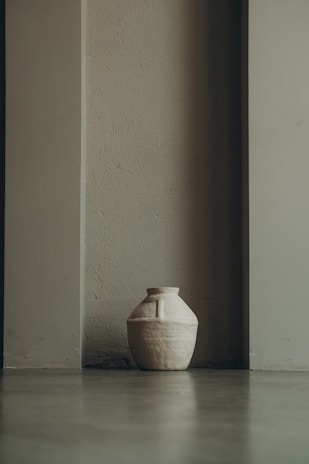 A bespoke ceramic vase glazed in earthy tones, resting on a rustic wooden table.