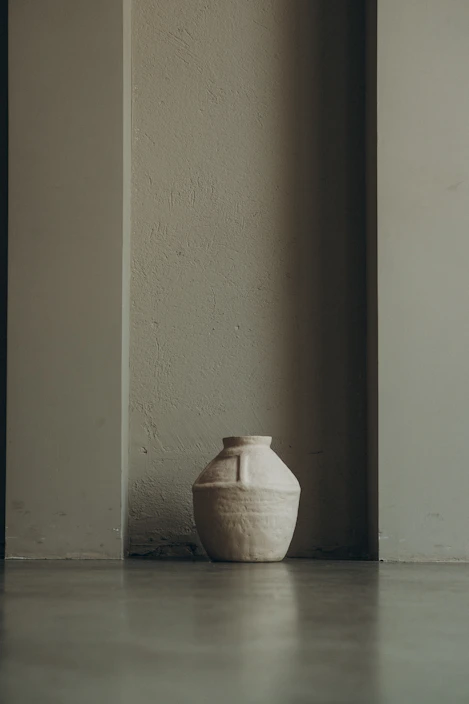 A rustic handmade ceramic vase with earthy tones on a wooden table.