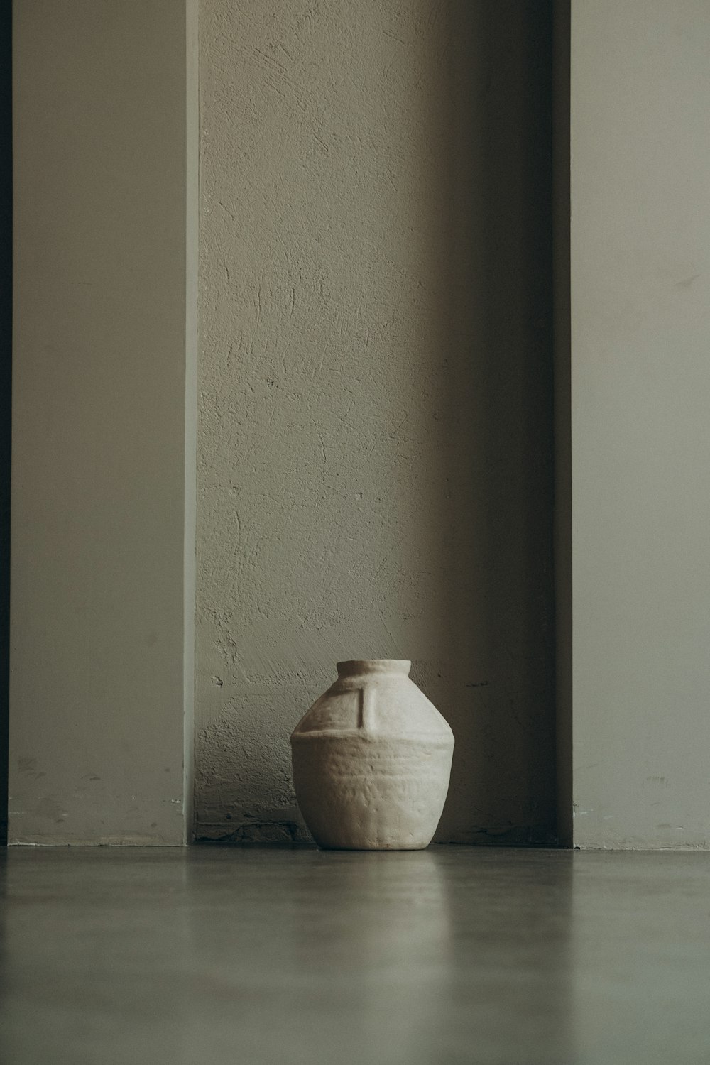 white ceramic vase on gray concrete floor