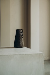 black ceramic figurine on white concrete table