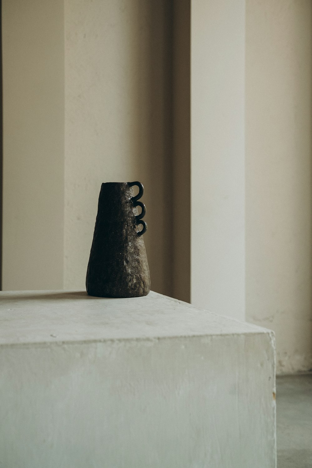 estatueta cerâmica preta na mesa branca do concreto
