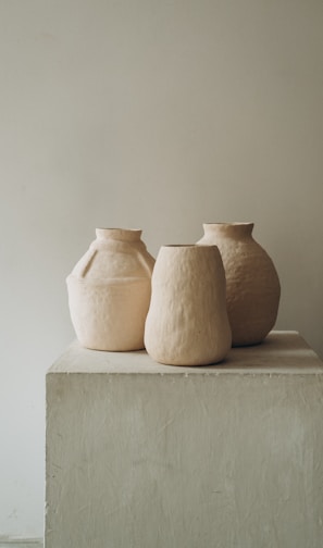 3 brown clay vases on white concrete table