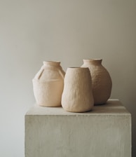 3 brown clay vases on white concrete table