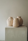 3 brown clay vases on white concrete table