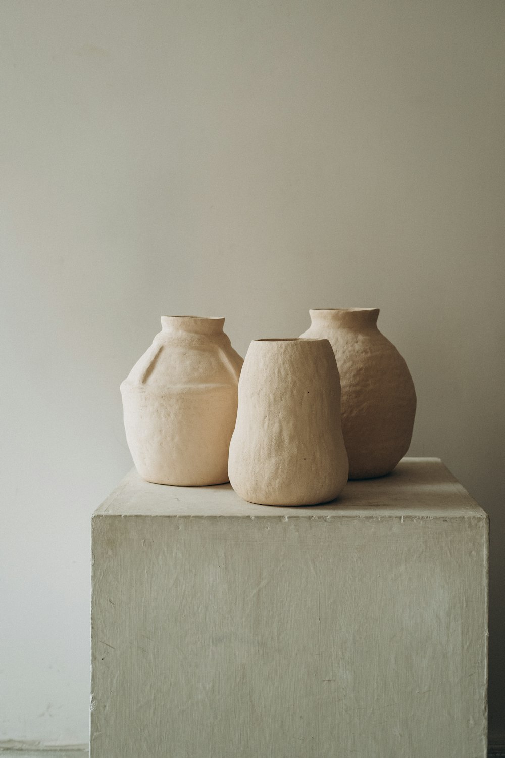 3 vases en argile brune sur table en béton blanc