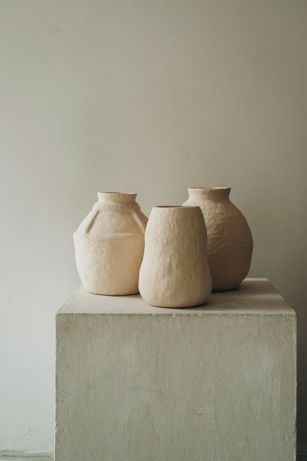 3 vasos de barro marrom na mesa de concreto branco