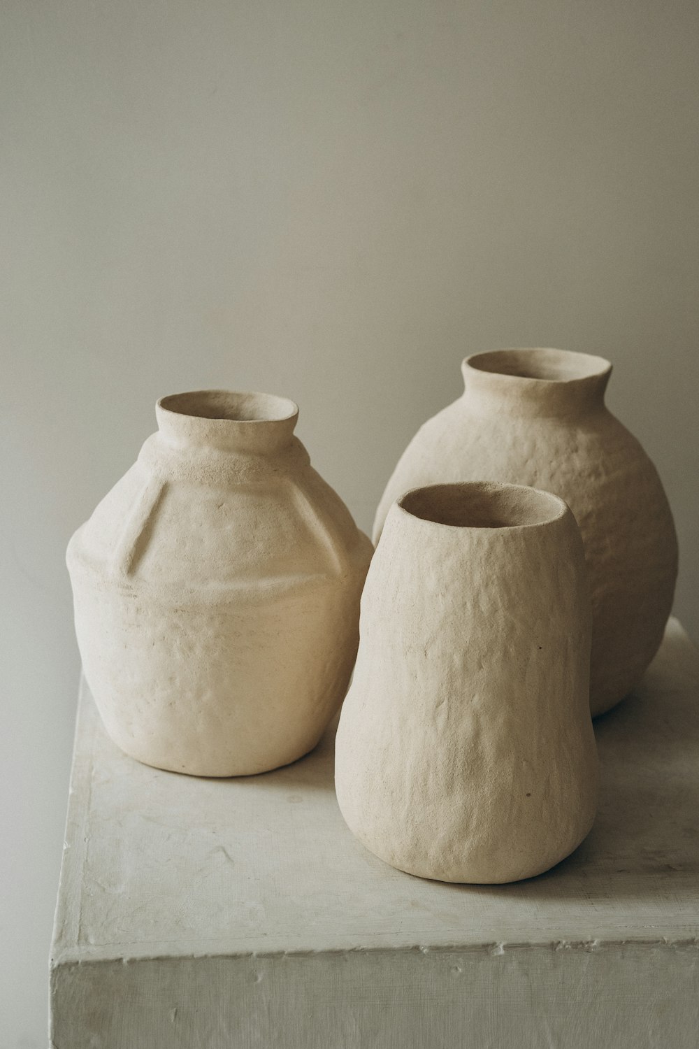 3 white ceramic jars on white table