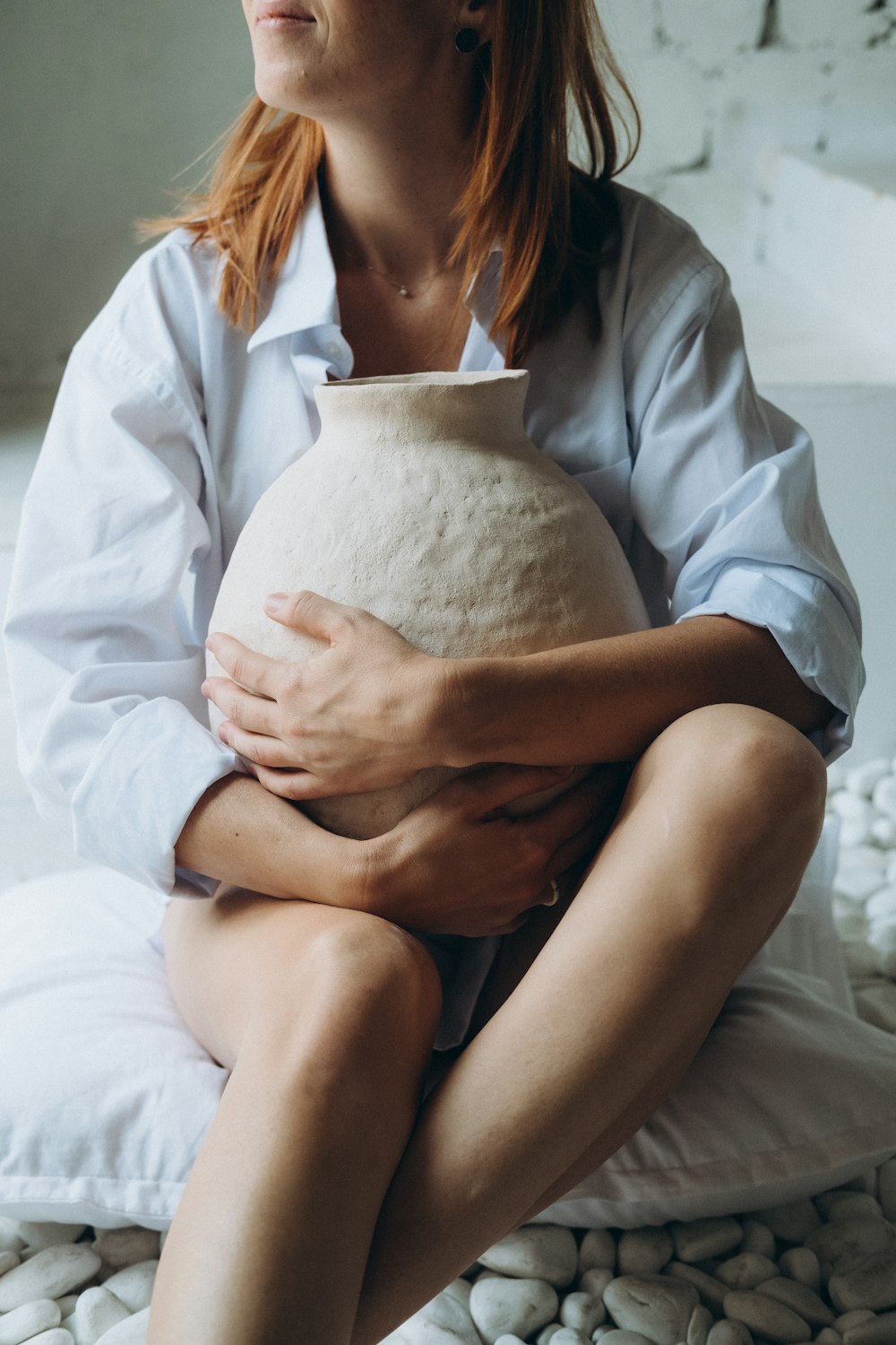 woman in white robe holding white round pillow