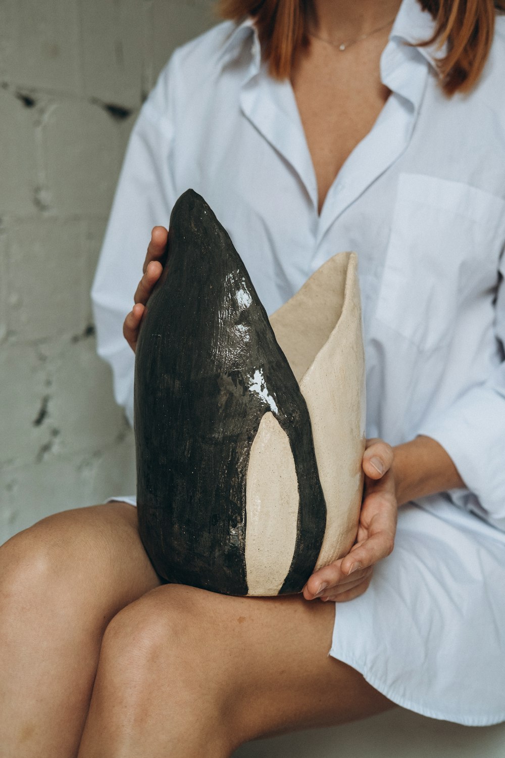 person in white button up shirt holding black and white stone