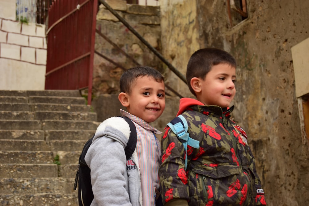 2 boys standing near brown wooden fence during daytime