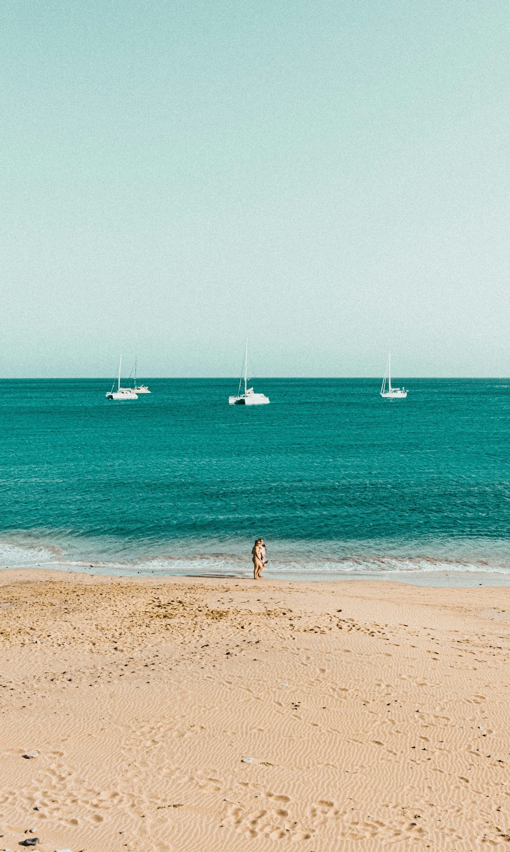 donna in bikini blu che cammina sulla spiaggia durante il giorno
