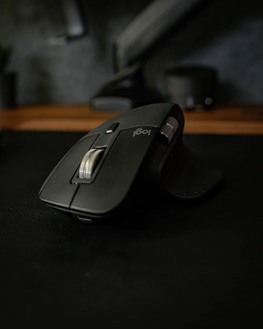 A modern wireless mouse resting on a minimalist mousepad with a blurred background.