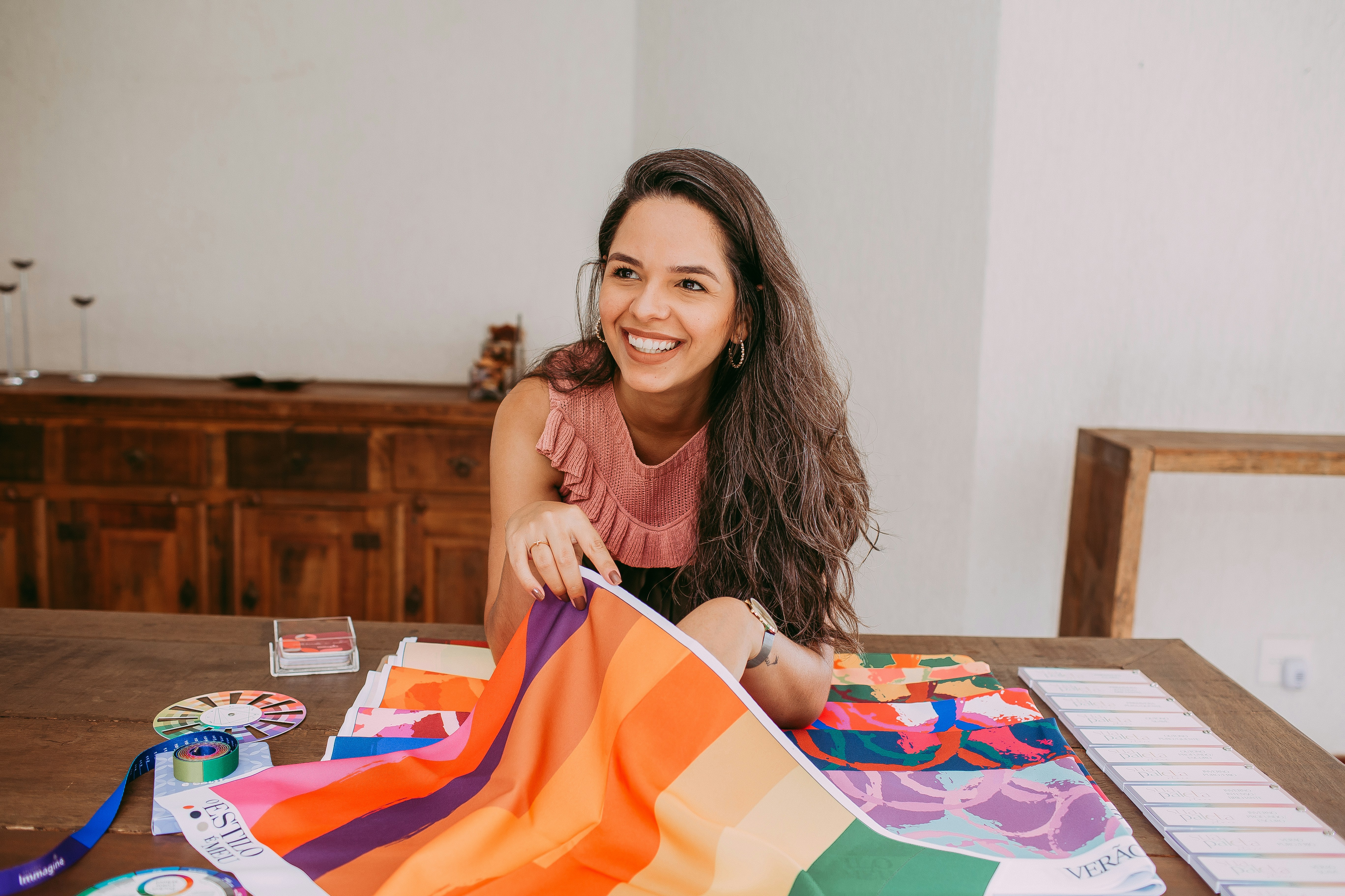 Woman working at a table surrounded by colorful rug tufting materials.