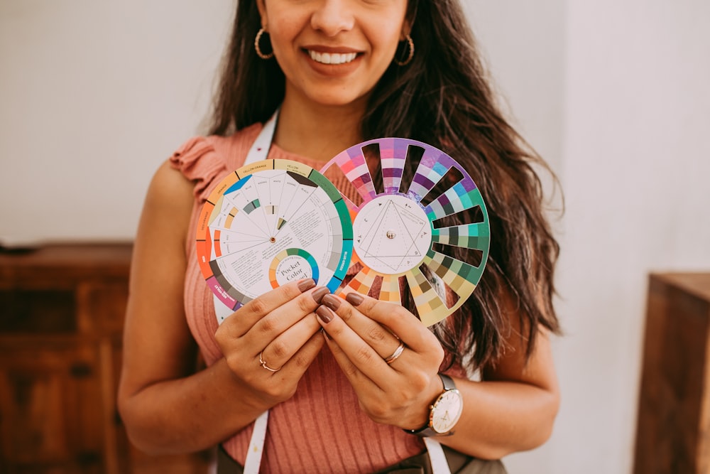 smiling woman in red and white stripe tank top holding round analog clock