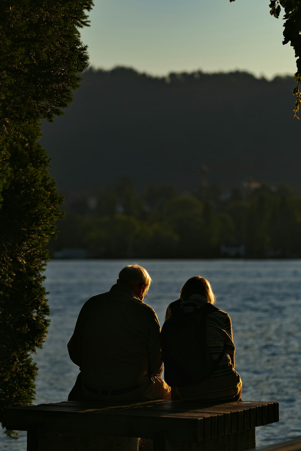 uomo e donna in piedi vicino allo specchio d'acqua durante il giorno