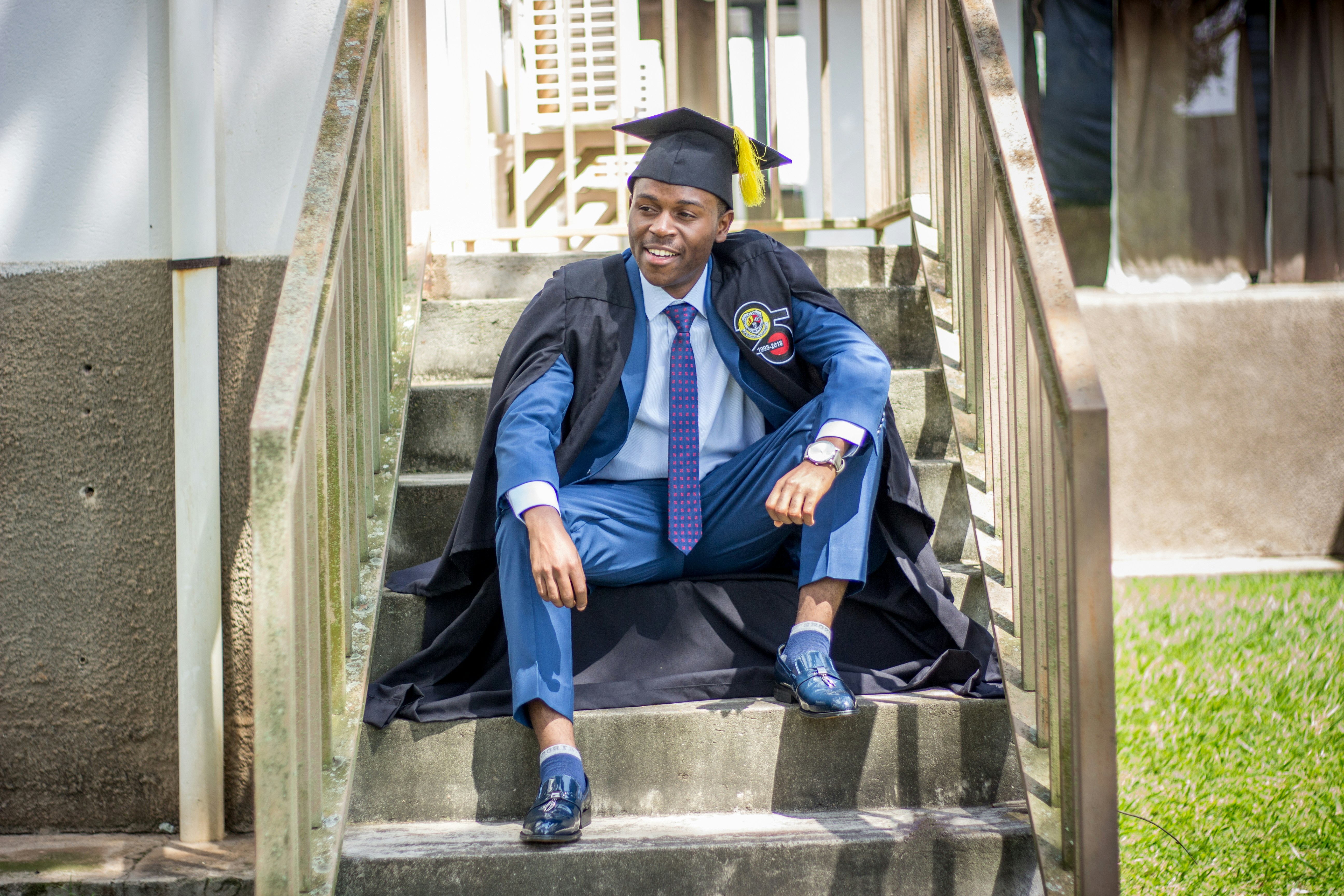 a man in a graduation cap and gown sitting on steps