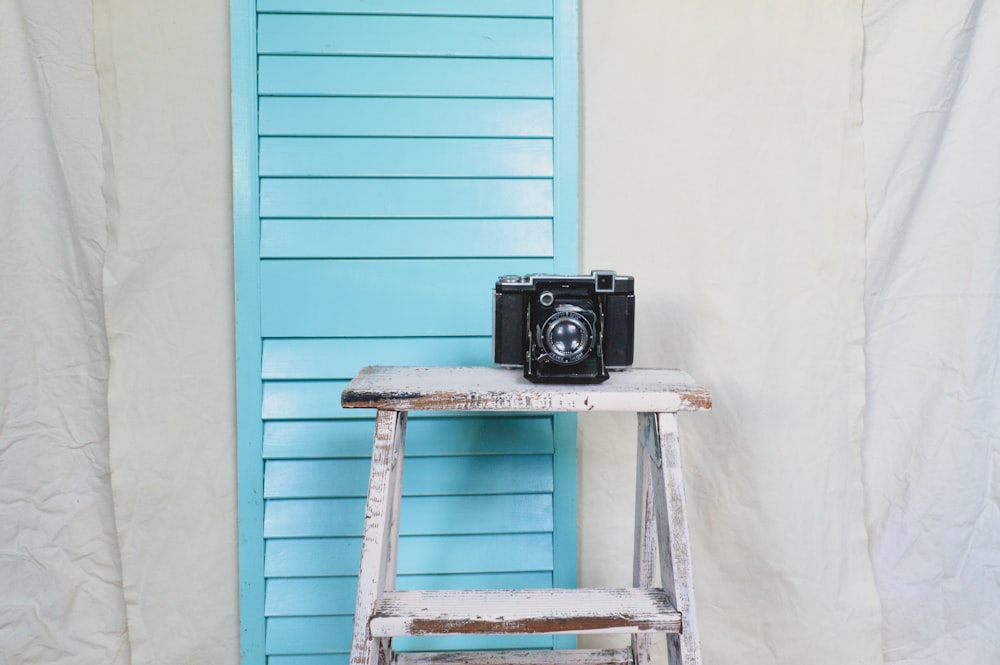 macchina fotografica nera e grigia su scala di legno blu