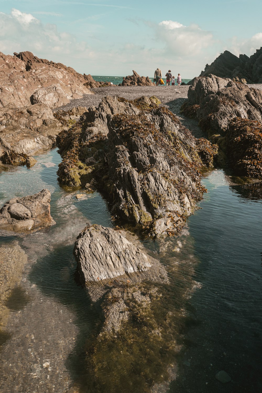 people standing on brown rock formation near body of water during daytime