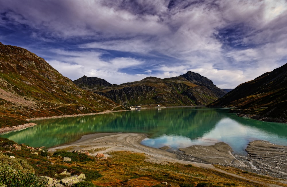 green and brown mountains beside lake under cloudy sky during daytime