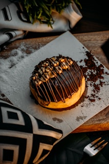 A lumberjack-themed donut topped with smoked maple glaze and a small edible pinecone decoration