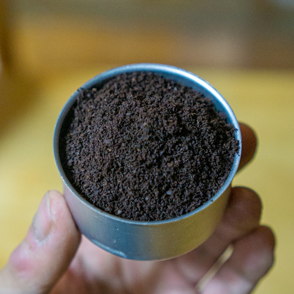 person holding black and silver round container